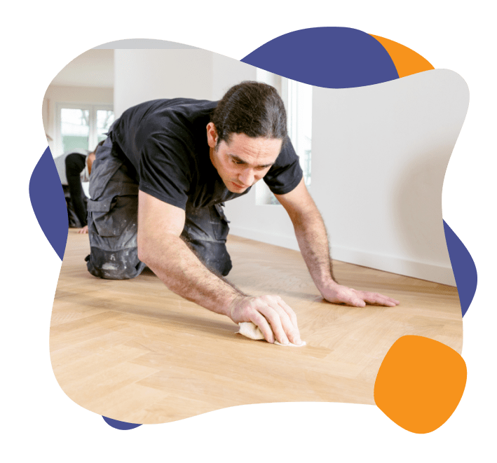 一名男子正在擦洗新安装的硬木地板上的胶渍. 